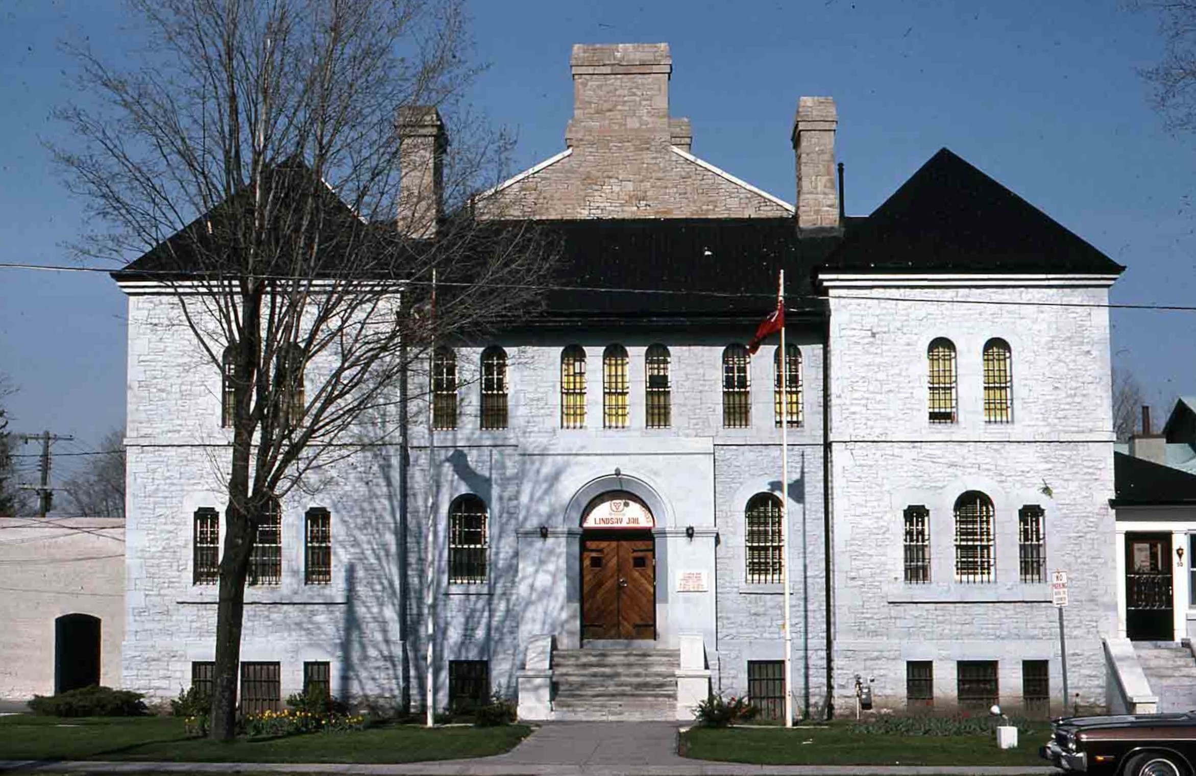 A symmetrical white-painted stone building with arched windows, a large door in the middle, and two gable roofs on either side.